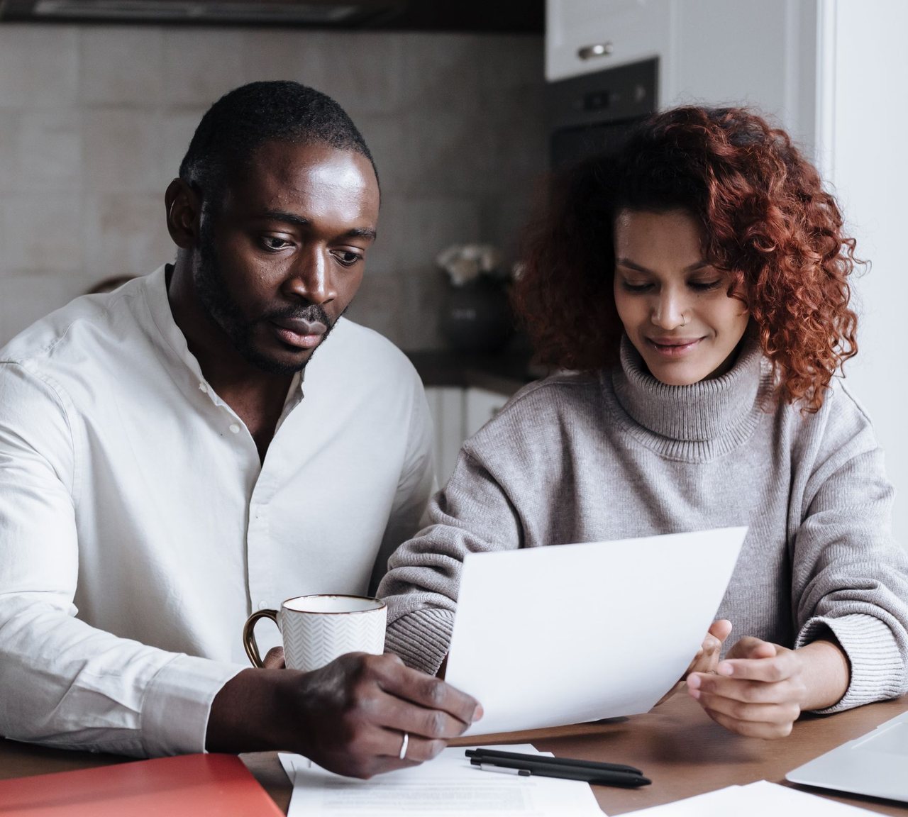 A couple reading a document together at their kitchen table