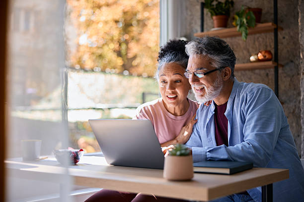 A retired couple smiling at a laptop at home