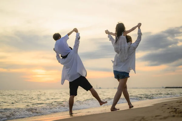 A family playing on the beach at sunset